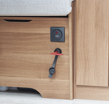 Preview: Roter Kunststoffschlüssel steckt im Trennschalter in einem Camper