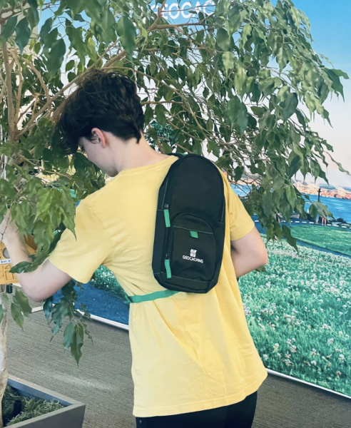 Geocacher trägt Sling Bag beim Suchen eines Caches